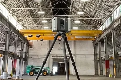 3D laser scanner on a tripod capturing the interior of a large industrial building
